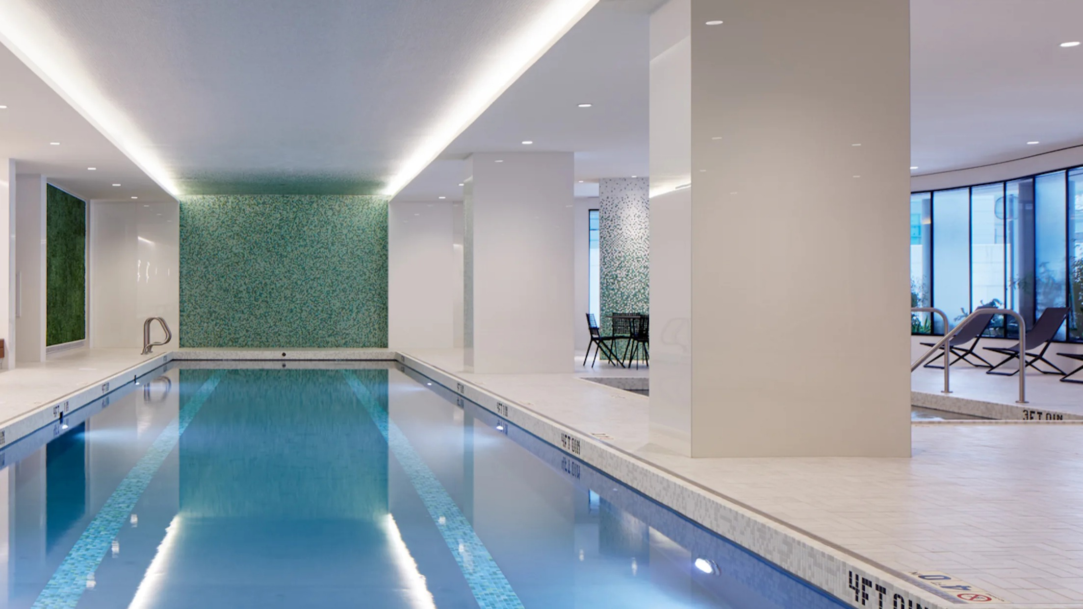 Pristine indoor lap pool with modern lighting and lounge chairs, perfect for year-round swimming at Cascade Lakeshore East in Chicago