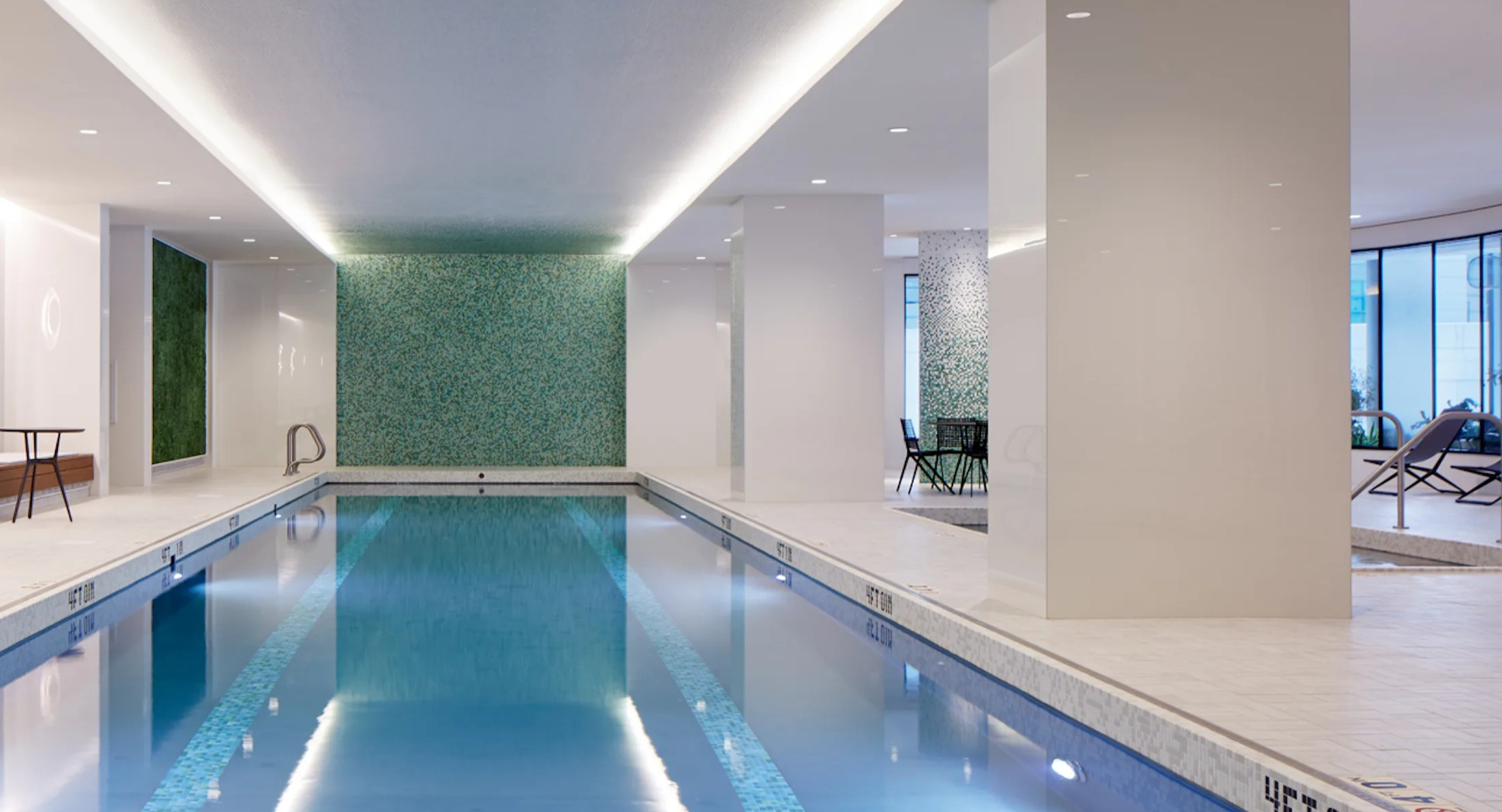 Pristine indoor lap pool with modern lighting and lounge chairs, perfect for year-round swimming at Cascade Lakeshore East in Chicago