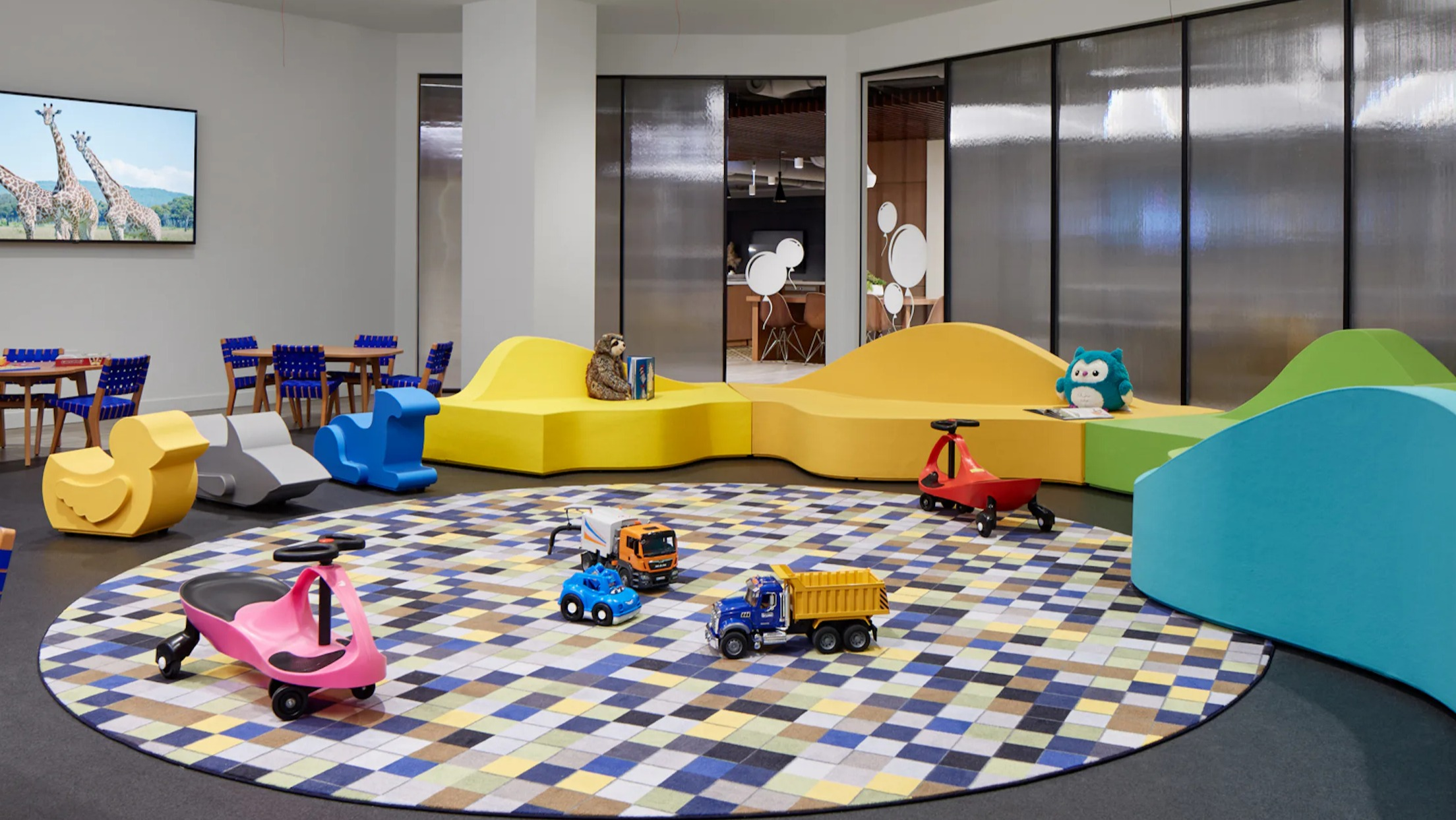 Bright and colorful kids' playroom with various toys, seating, and a fun rug at Cascade Lakeshore East in Chicago