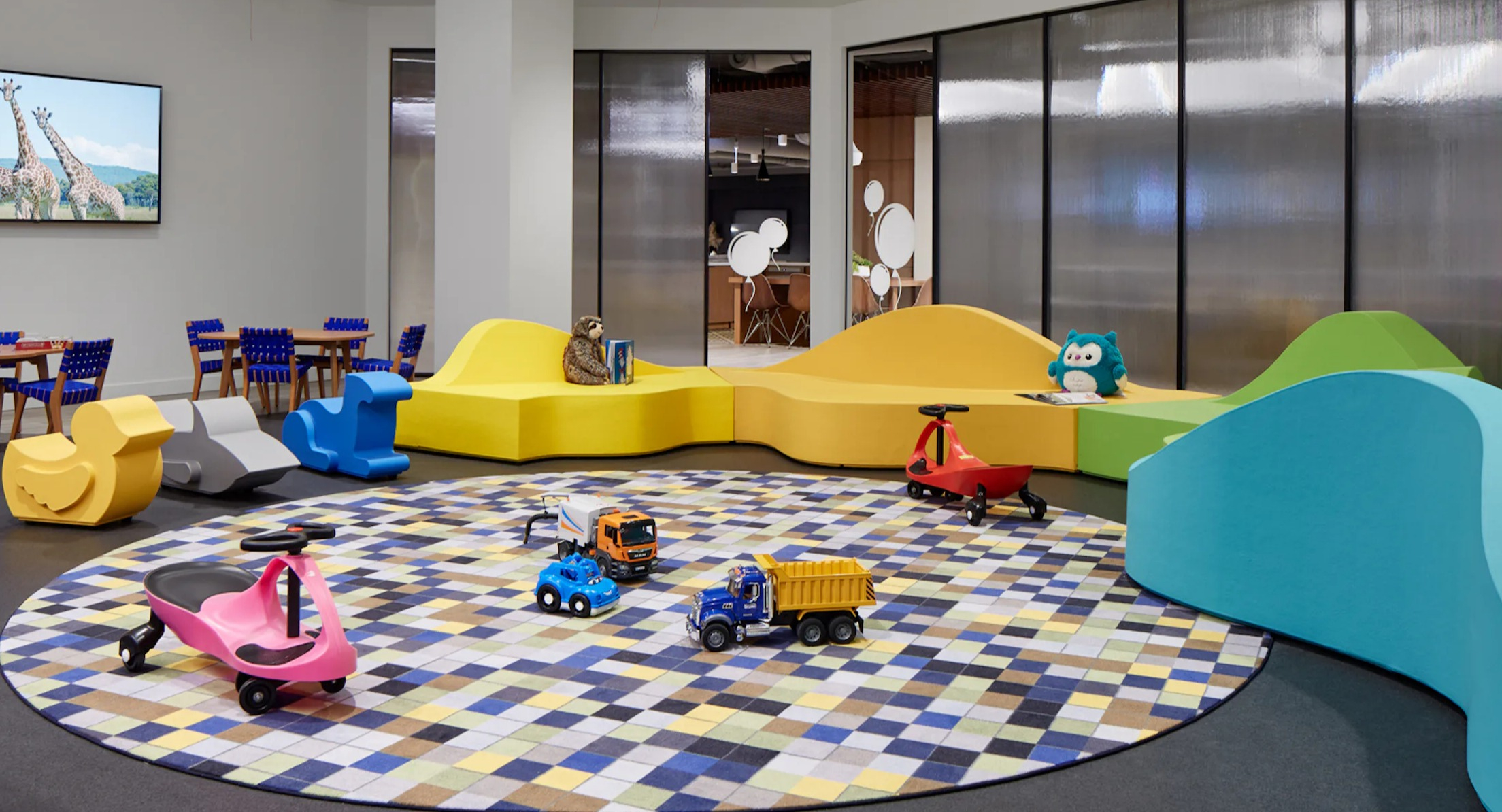 Bright and colorful kids' playroom with various toys, seating, and a fun rug at Cascade Lakeshore East in Chicago