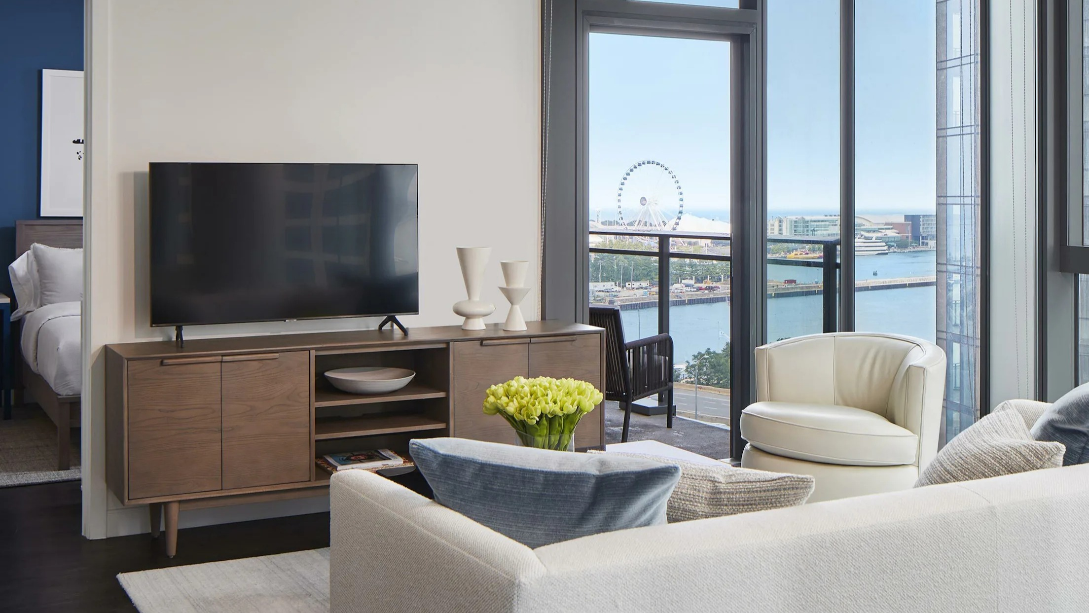 Bright living room with comfortable seating, a television, and a balcony offering lake views at Cascade Lakeshore East in Chicago