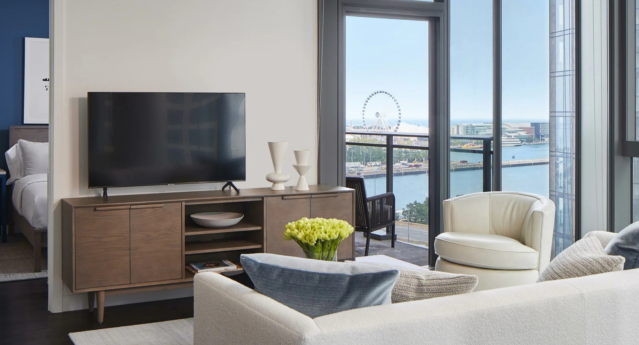 Bright living room with comfortable seating, a television, and a balcony offering lake views at Cascade Lakeshore East in Chicago