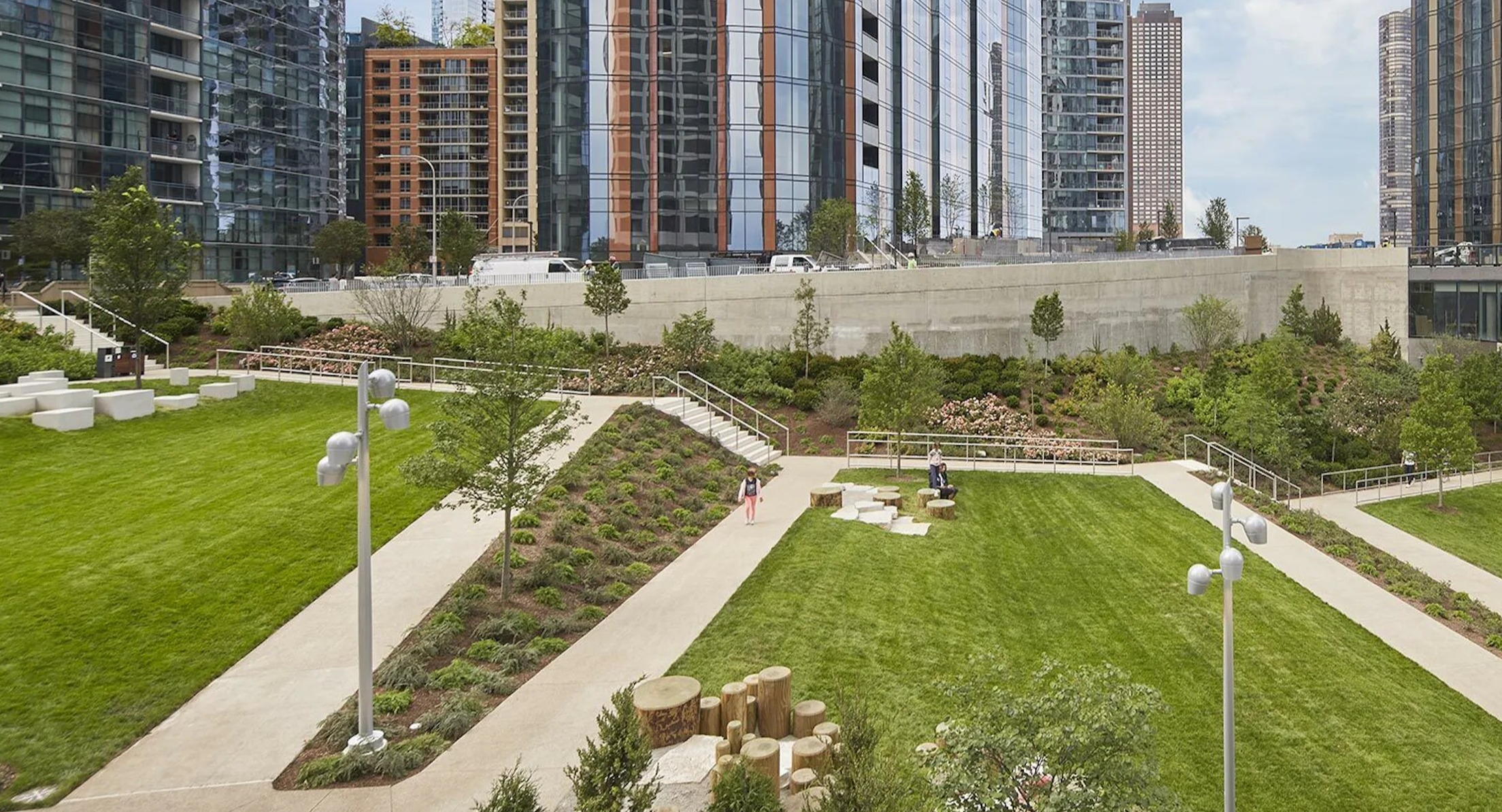 Lush green park space with walking paths and seating areas, nestled between modern high-rise buildings in Chicago