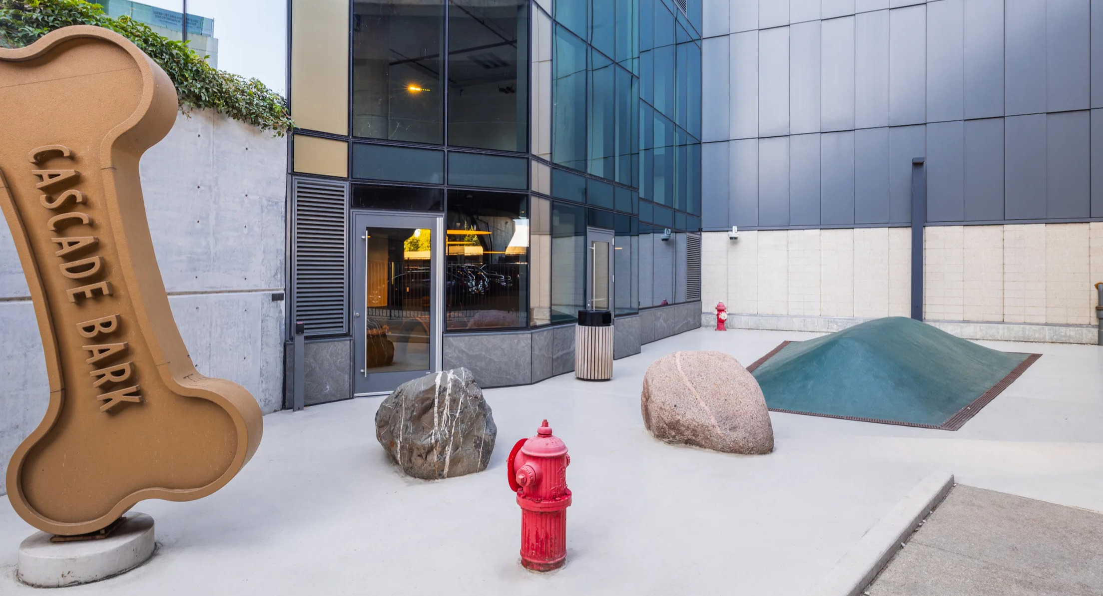 Outdoor pet-friendly dog park area with a large bone sculpture and play mounds at Cascade Lakeshore East in Chicago