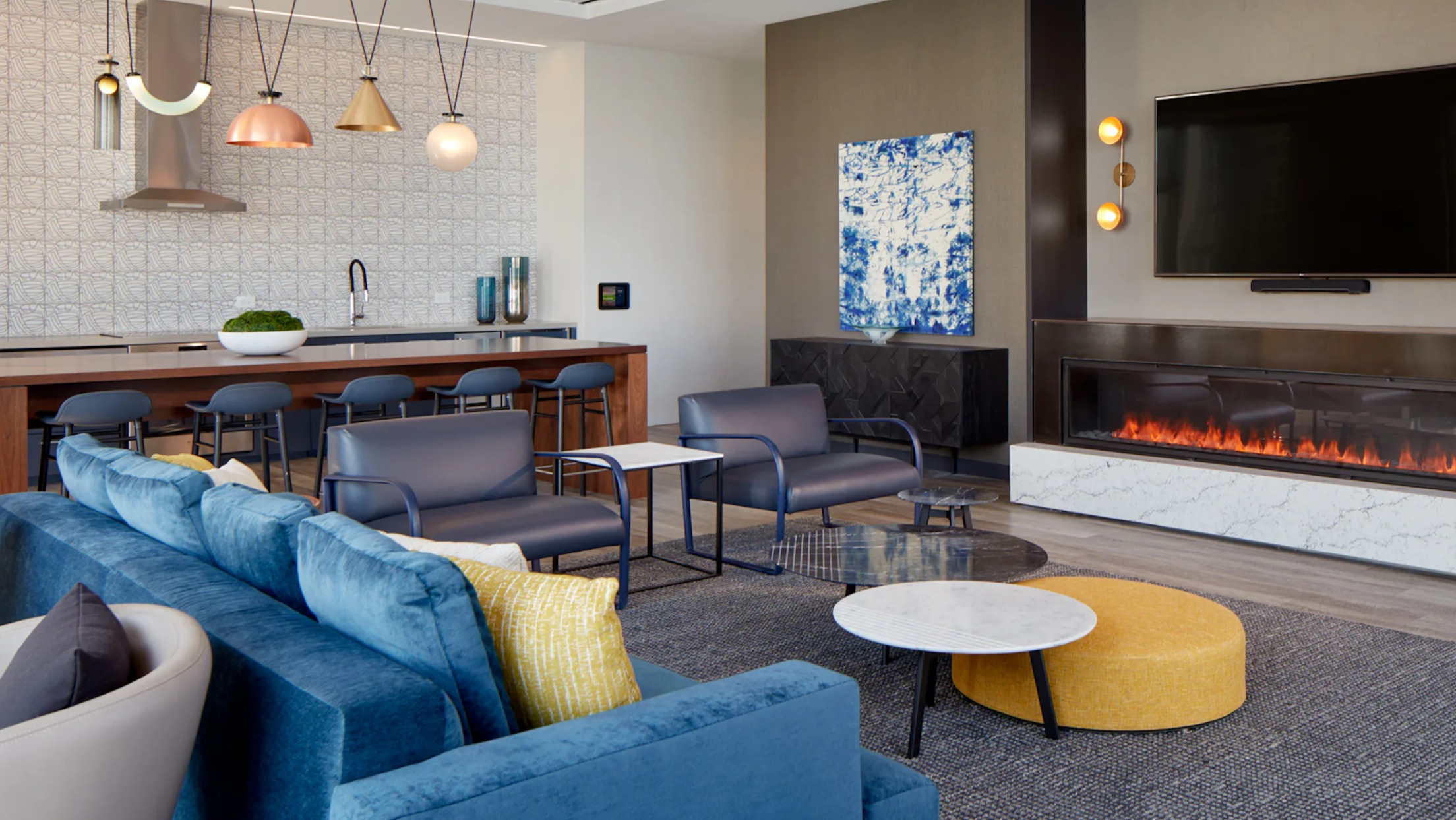 Stylish resident lounge with a cozy fireplace, comfortable seating, and a modern kitchen area at Cascade Lakeshore East in Chicago