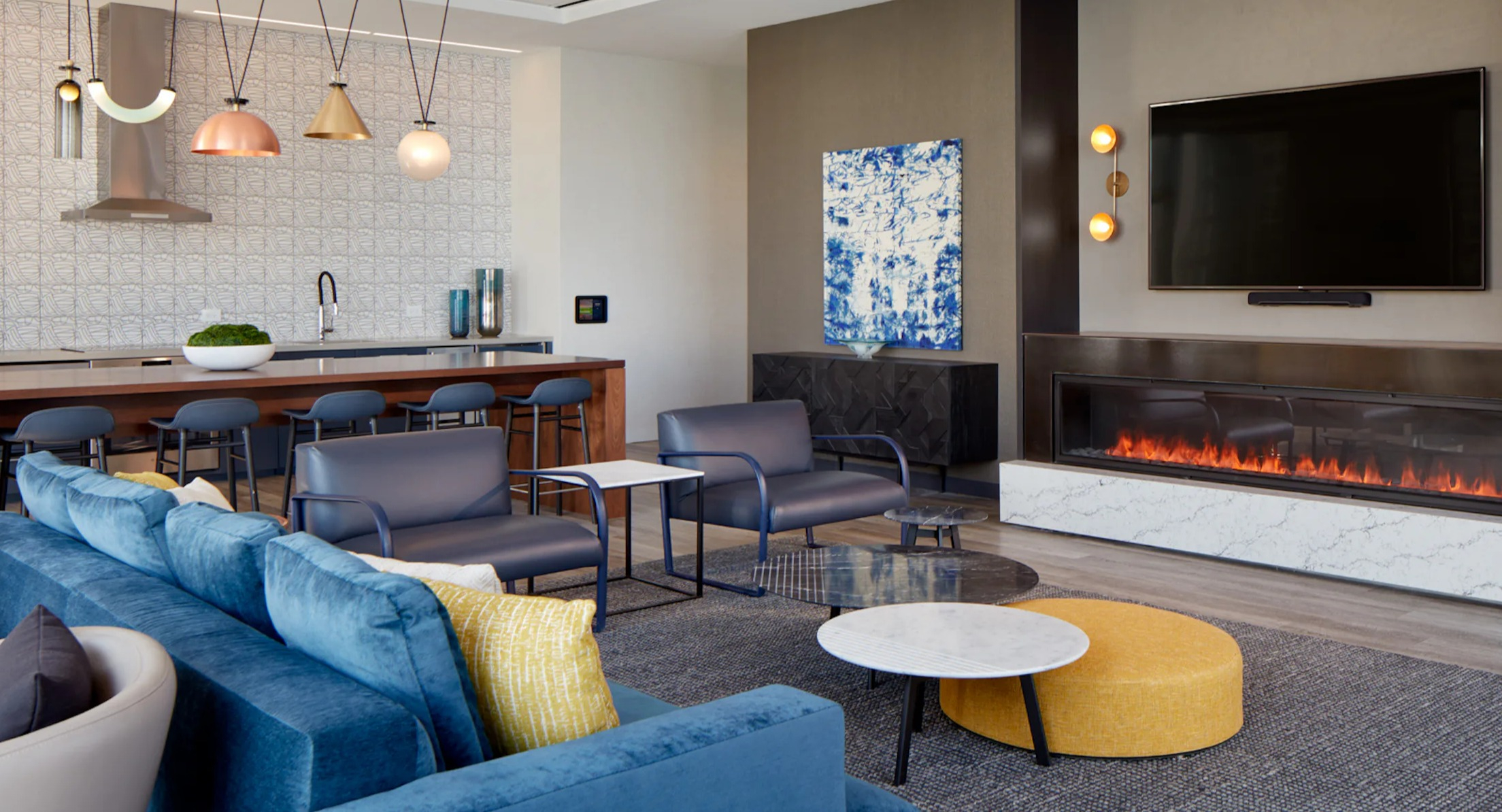 Stylish resident lounge with a cozy fireplace, comfortable seating, and a modern kitchen area at Cascade Lakeshore East in Chicago