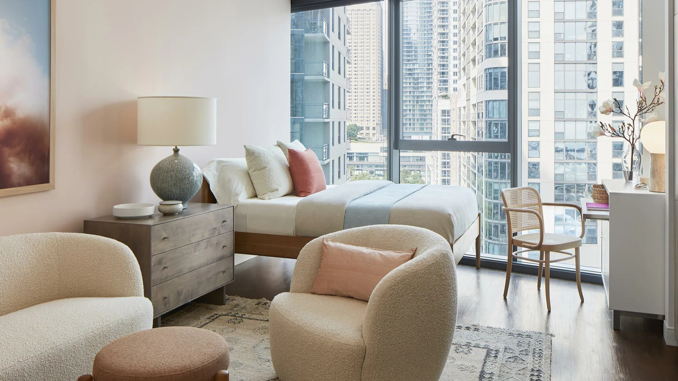 Stylish studio apartment bedroom area with a comfortable bed, seating, and large windows at Cascade Lakeshore East in Chicago