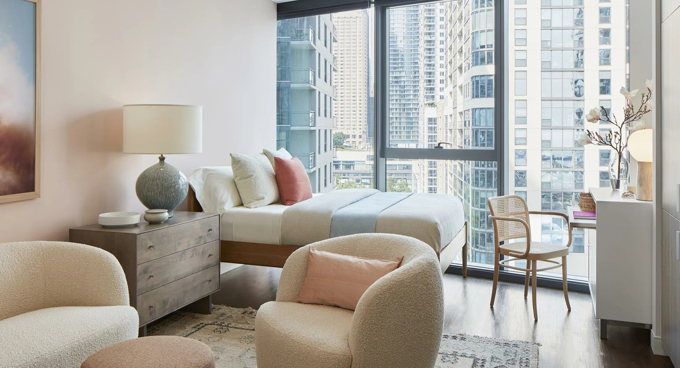 Stylish studio apartment bedroom area with a comfortable bed, seating, and large windows at Cascade Lakeshore East in Chicago