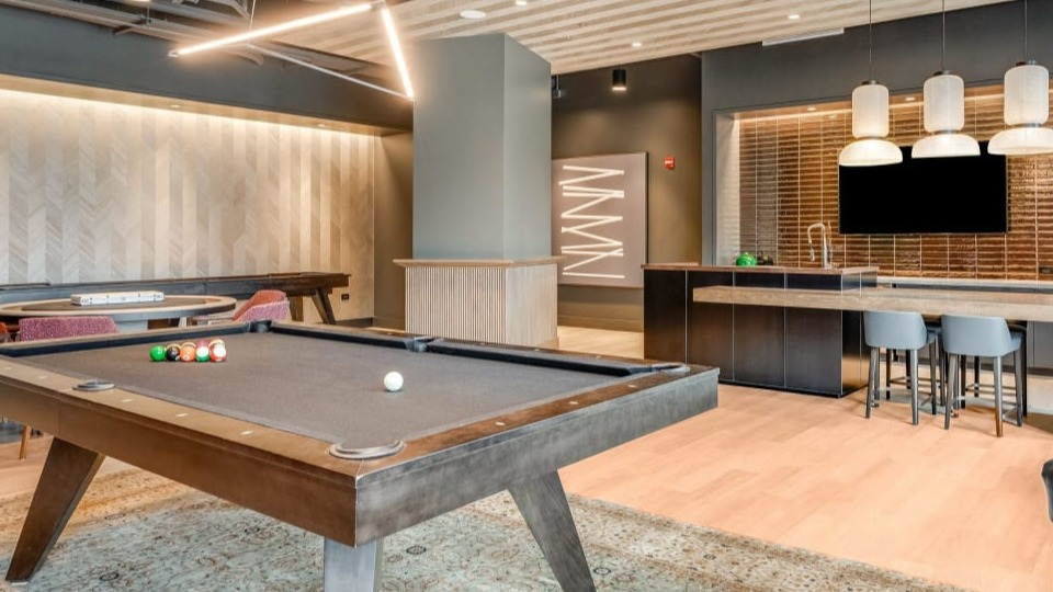 Modern resident lounge featuring a billiards table, comfortable seating areas, and a communal kitchen space at Cassidy on Canal apartments in Chicago