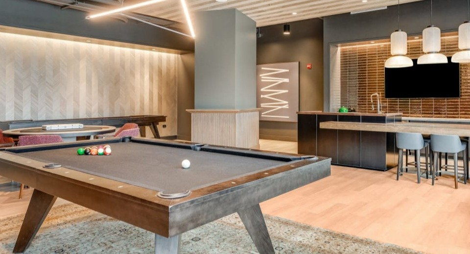 Modern resident lounge featuring a billiards table, comfortable seating areas, and a communal kitchen space at Cassidy on Canal apartments in Chicago