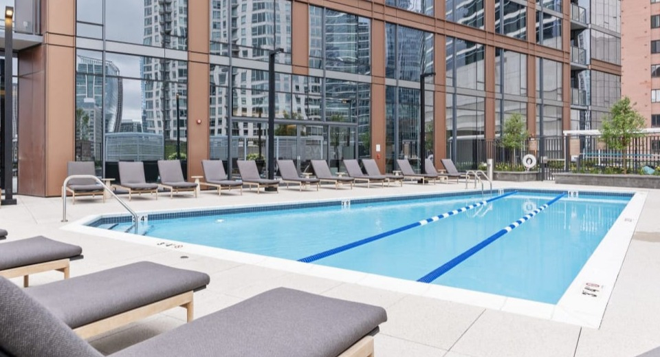 Outdoor swimming pool surrounded by modern lounge seating, set against the striking exterior of Cassidy on Canal apartments in Chicago