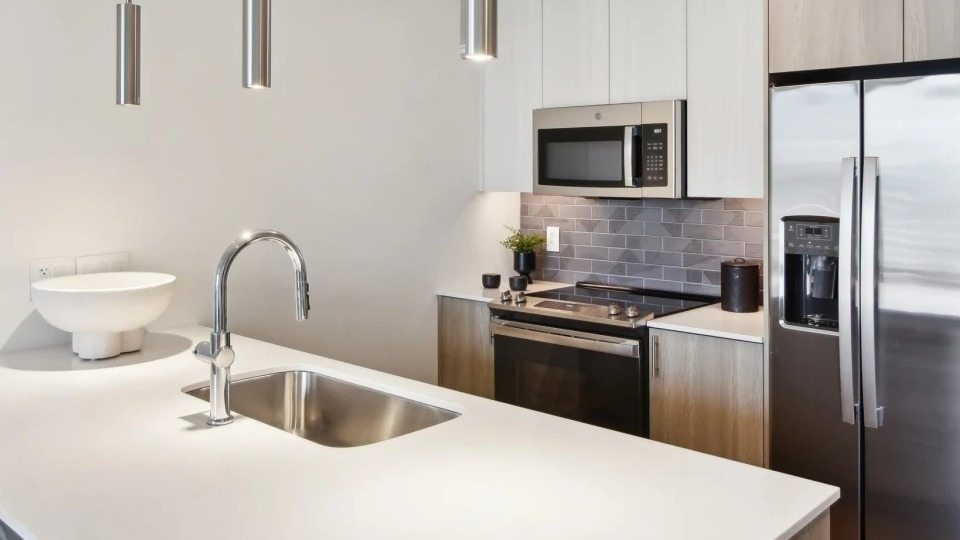 Contemporary apartment kitchen featuring a large island with a sink, stainless steel appliances, and minimalist design at Cassidy on Canal in Chicago