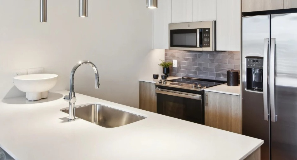 Contemporary apartment kitchen featuring a large island with a sink, stainless steel appliances, and minimalist design at Cassidy on Canal in Chicago