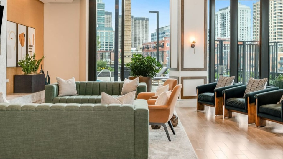 Elegant resident lounge with modern furnishings, a stylish fireplace, and expansive windows overlooking the city at Cassidy on Canal in Chicago