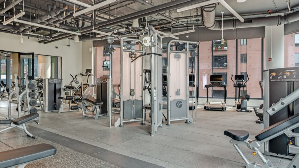 Well-equipped apartment gym featuring a variety of strength training machines and free weights for a full workout at Cassidy on Canal apartments in Chicago