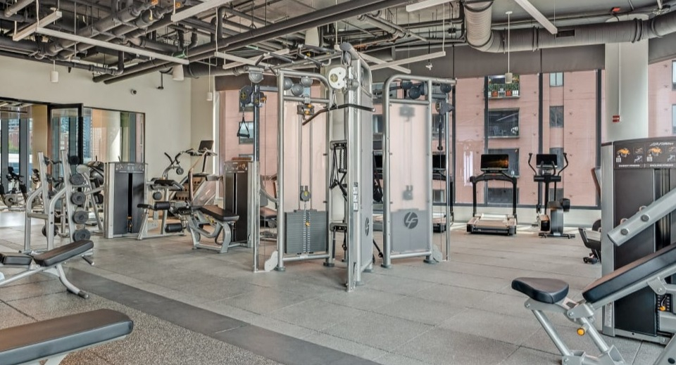 Well-equipped apartment gym featuring a variety of strength training machines and free weights for a full workout at Cassidy on Canal apartments in Chicago