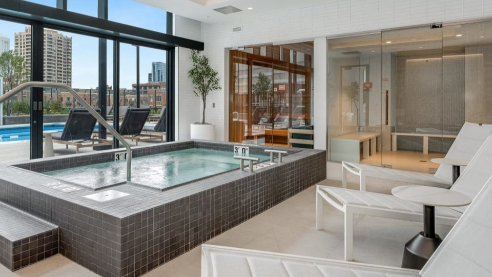 Luxurious indoor spa area with a large hot tub and comfortable lounge chairs, offering relaxation at Cassidy on Canal apartments in Chicago