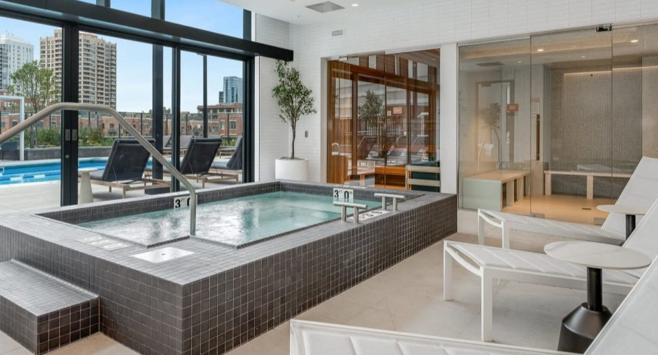 Luxurious indoor spa area with a large hot tub and comfortable lounge chairs, offering relaxation at Cassidy on Canal apartments in Chicago