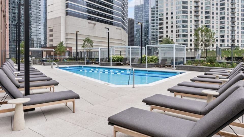 Expansive outdoor pool deck featuring numerous comfortable lounge chairs and stylish pergolas at Cassidy on Canal apartments in Chicago