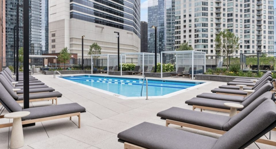 Expansive outdoor pool deck featuring numerous comfortable lounge chairs and stylish pergolas at Cassidy on Canal apartments in Chicago