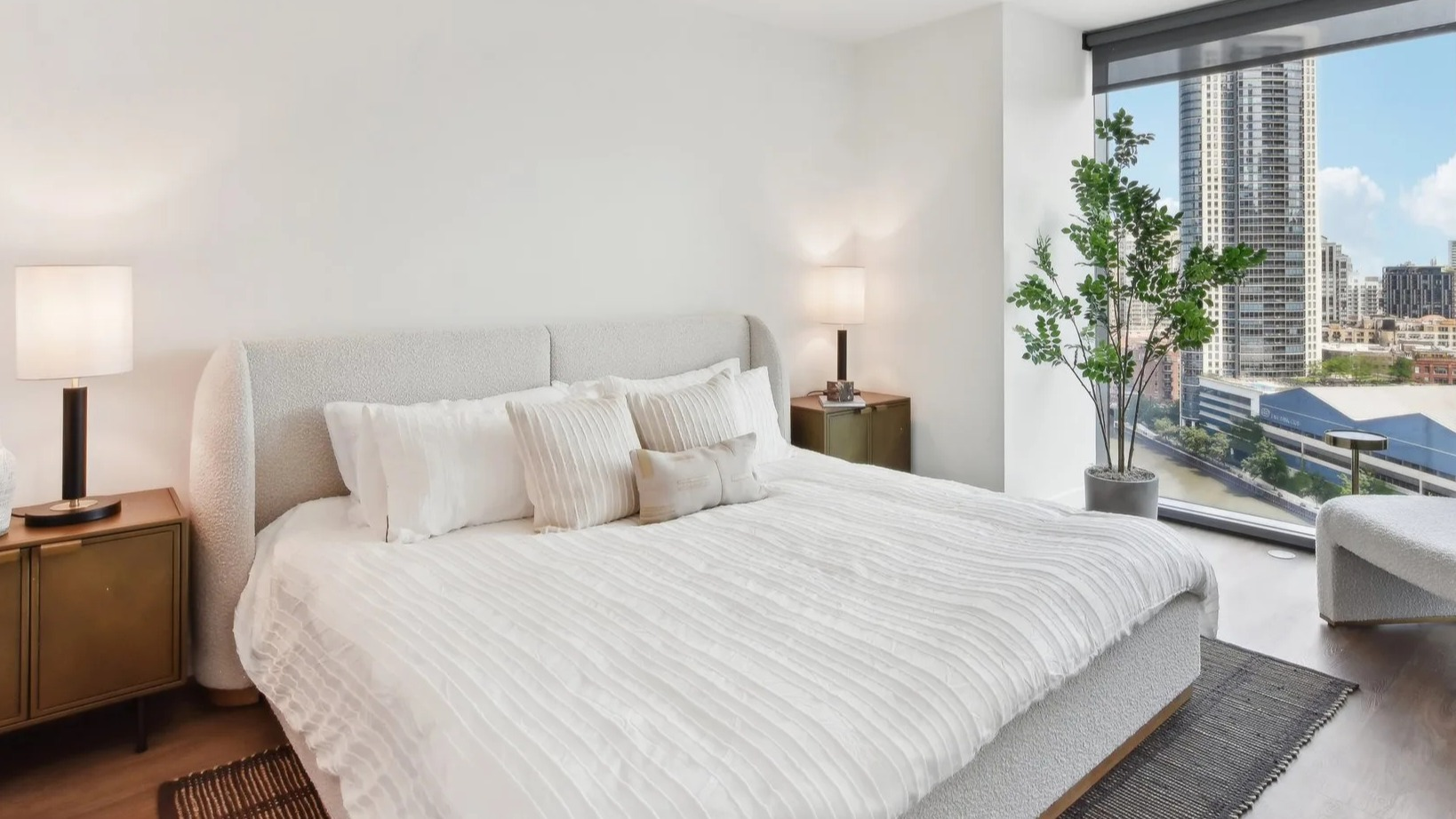 Elegant master bedroom featuring a large bed, stylish decor, and expansive windows offering stunning cityscape views at Cassidy on Canal in Chicago