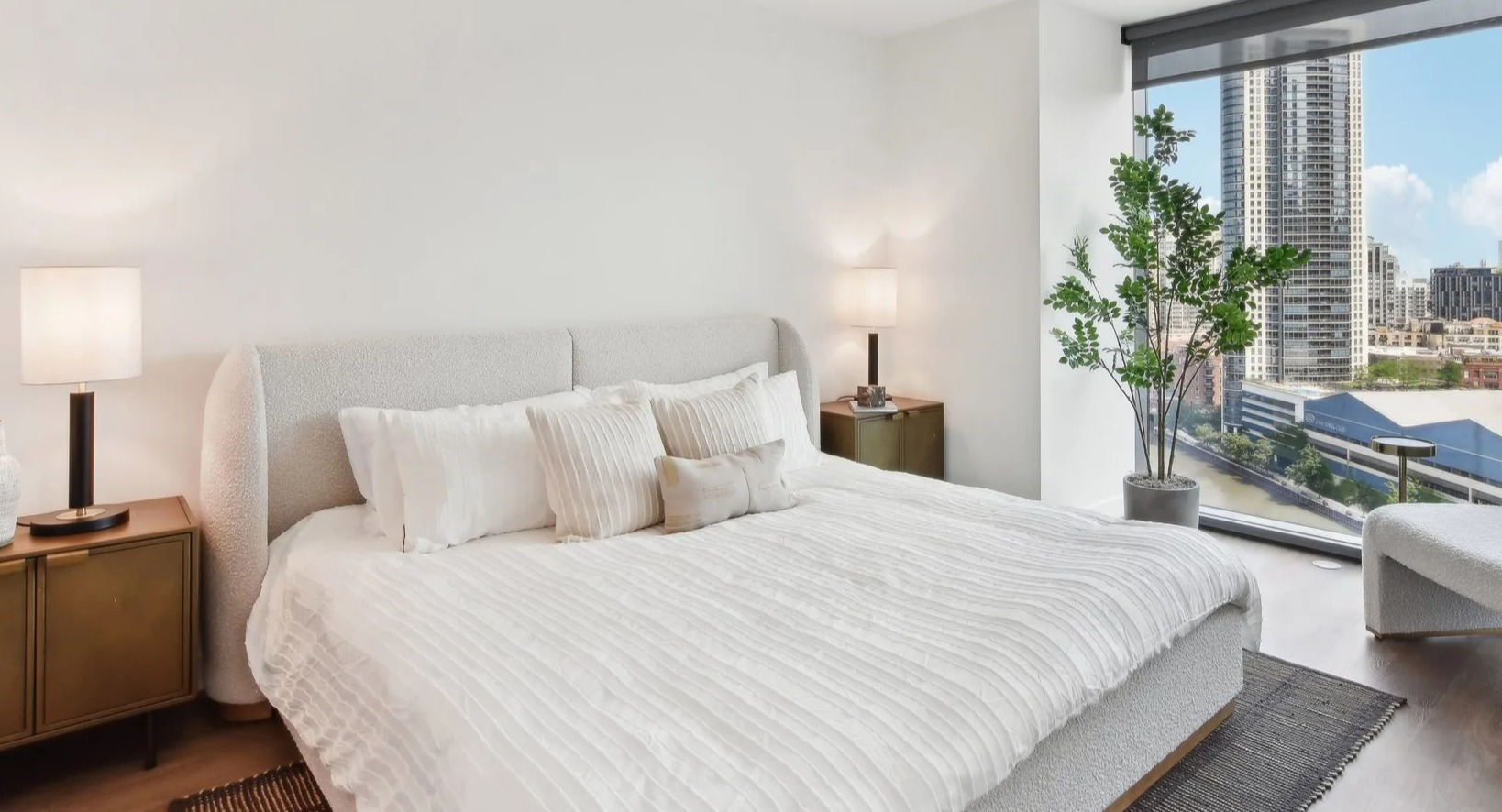 Elegant master bedroom featuring a large bed, stylish decor, and expansive windows offering stunning cityscape views at Cassidy on Canal in Chicago