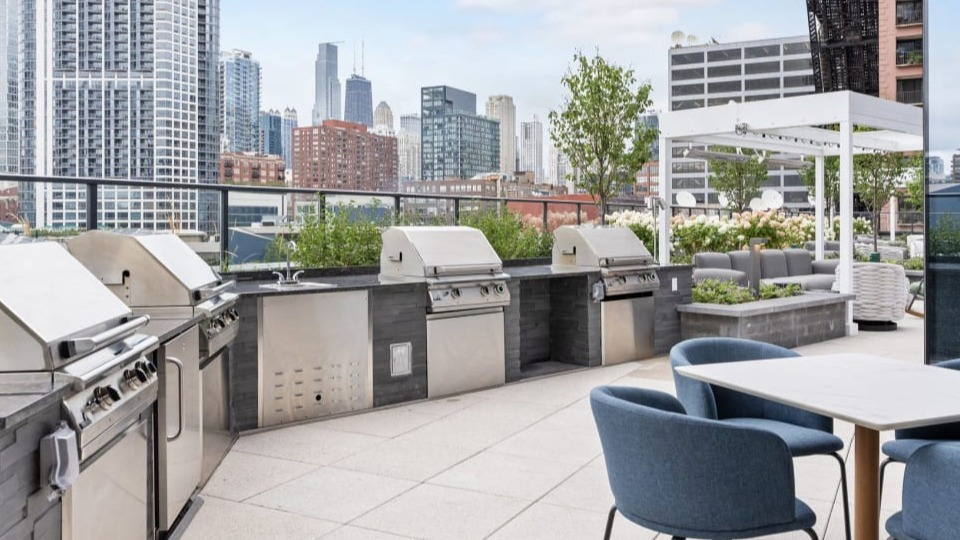Outdoor rooftop grilling station with multiple grills and a dining area, perfect for entertaining at Cassidy on Canal apartments in Chicago