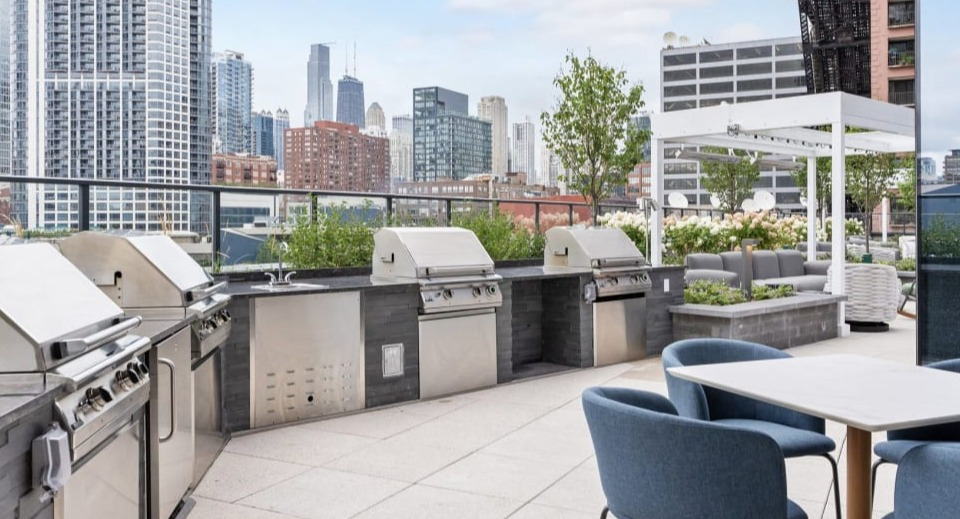 Outdoor rooftop grilling station with multiple grills and a dining area, perfect for entertaining at Cassidy on Canal apartments in Chicago