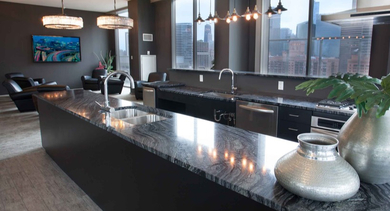 Stylish amenity kitchen and lounge area at Catalyst apartments in Chicago, featuring a large island, modern fixtures, and city views