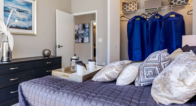 Cozy bedroom at Catalyst apartments in Chicago with a comfortable bed, dresser, and an open walk-in closet