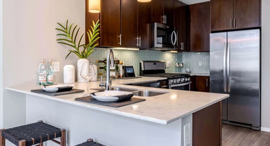 Modern kitchen at Catalyst apartments in Chicago featuring an island with bar seating, dark cabinetry, and sleek stainless steel appliances