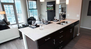 Modern kitchen with a large island overlooking a stylish living space at Catalyst apartments in Chicago, with hardwood floors