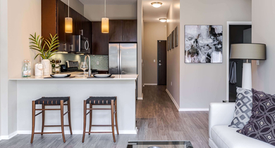 Modern open-layout kitchen and living room at Catalyst apartments in Chicago, with a breakfast bar and wood flooring