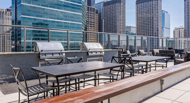 Rooftop BBQ area at Catalyst apartments in Chicago, featuring multiple grills, outdoor dining, and sweeping city views