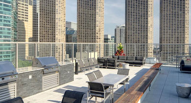 Rooftop amenity deck at Catalyst apartments in Chicago, complete with outdoor grills, dining tables, and comfortable seating