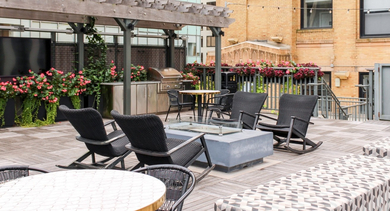 Outdoor lounge area on the rooftop deck featuring a fire pit, rocking chairs, and city views at Century Tower Apartments Chicago