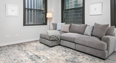 Spacious living room with a large grey sectional sofa, soft rug, and city views at Century Tower Apartments Chicago