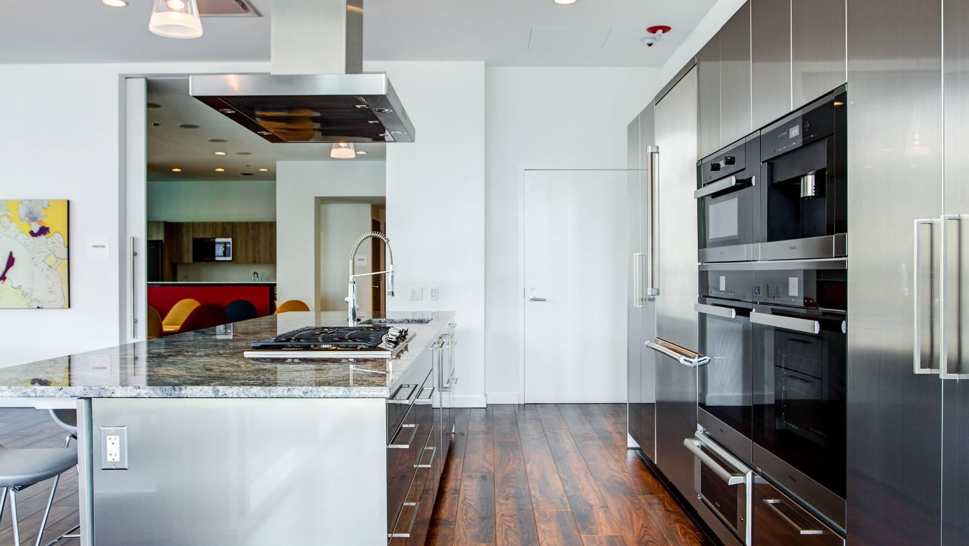 Gourmet demonstration kitchen with long island, stainless appliances, and seating for events at Optima Signature apartments in Chicago