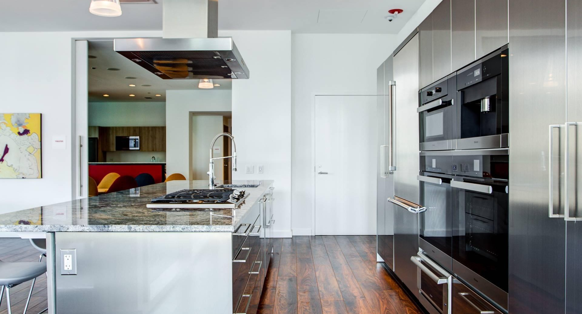 Gourmet demonstration kitchen with long island, stainless appliances, and seating for events at Optima Signature apartments in Chicago