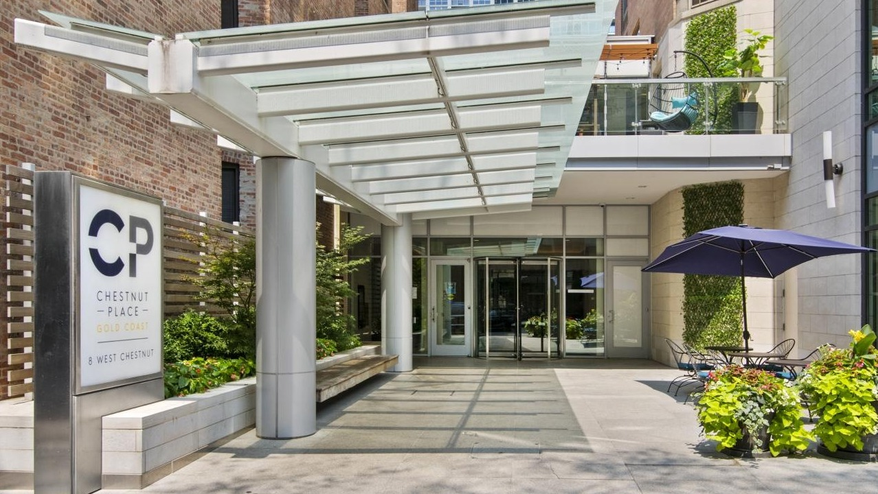 Inviting building entrance at Chestnut Place apartments in Chicago, with an awning and outdoor patio seating