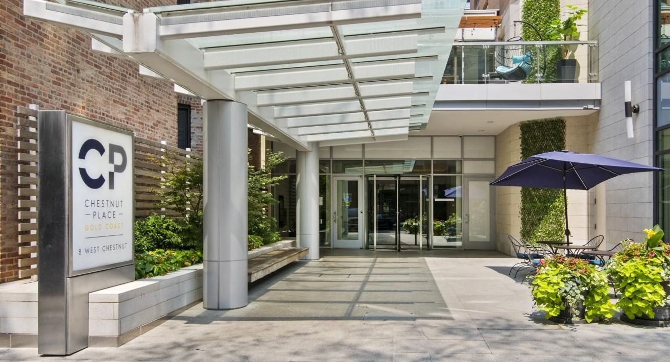 Inviting building entrance at Chestnut Place apartments in Chicago, with an awning and outdoor patio seating