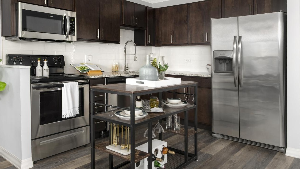 Galley kitchen at Chestnut Place apartments in Chicago with dark wood cabinets, stainless steel appliances, and a mobile island