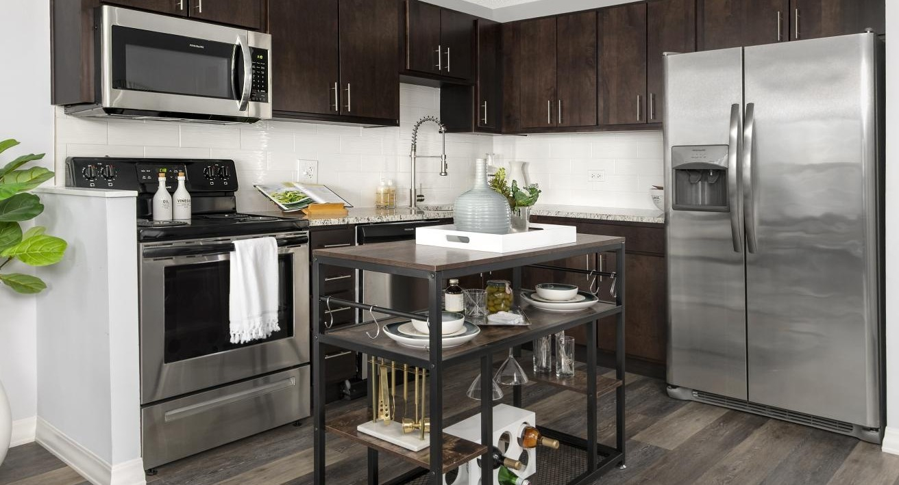 Galley kitchen at Chestnut Place apartments in Chicago with dark wood cabinets, stainless steel appliances, and a mobile island