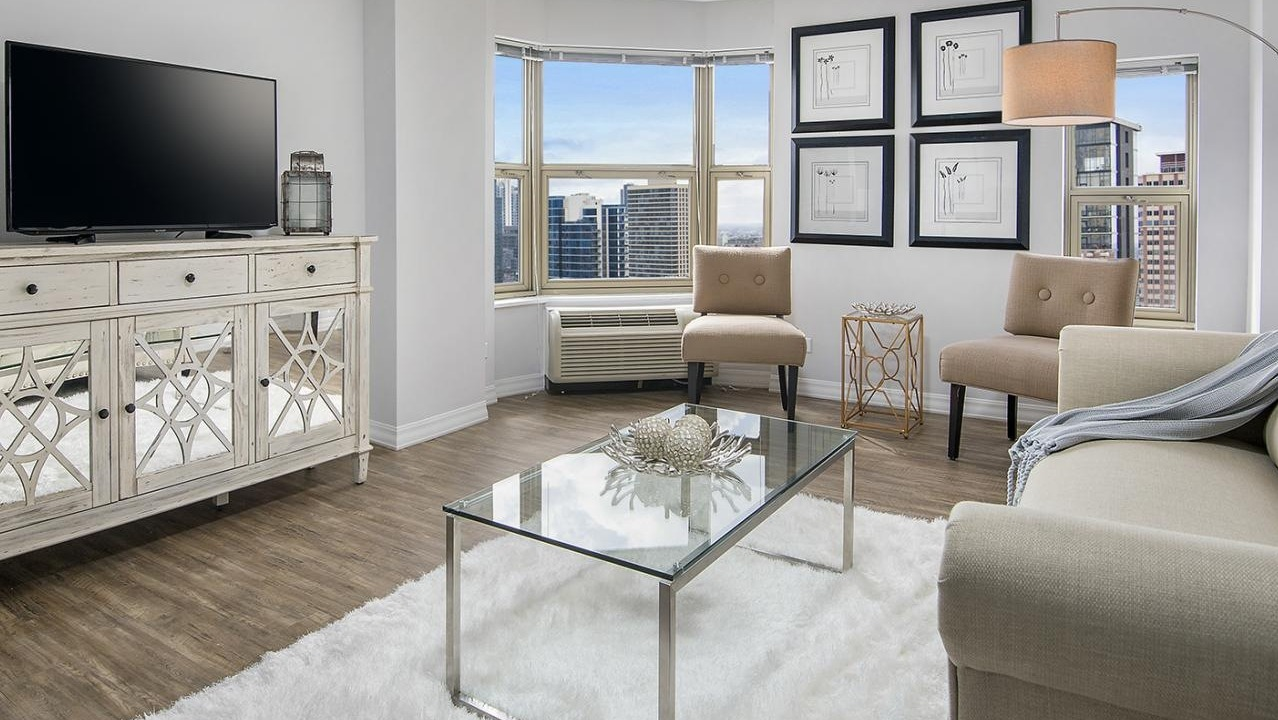 Bright living room at Chestnut Place apartments in Chicago with large bay windows offering city views and hardwood floors