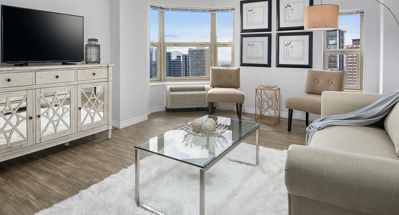 Bright living room at Chestnut Place apartments in Chicago with large bay windows offering city views and hardwood floors