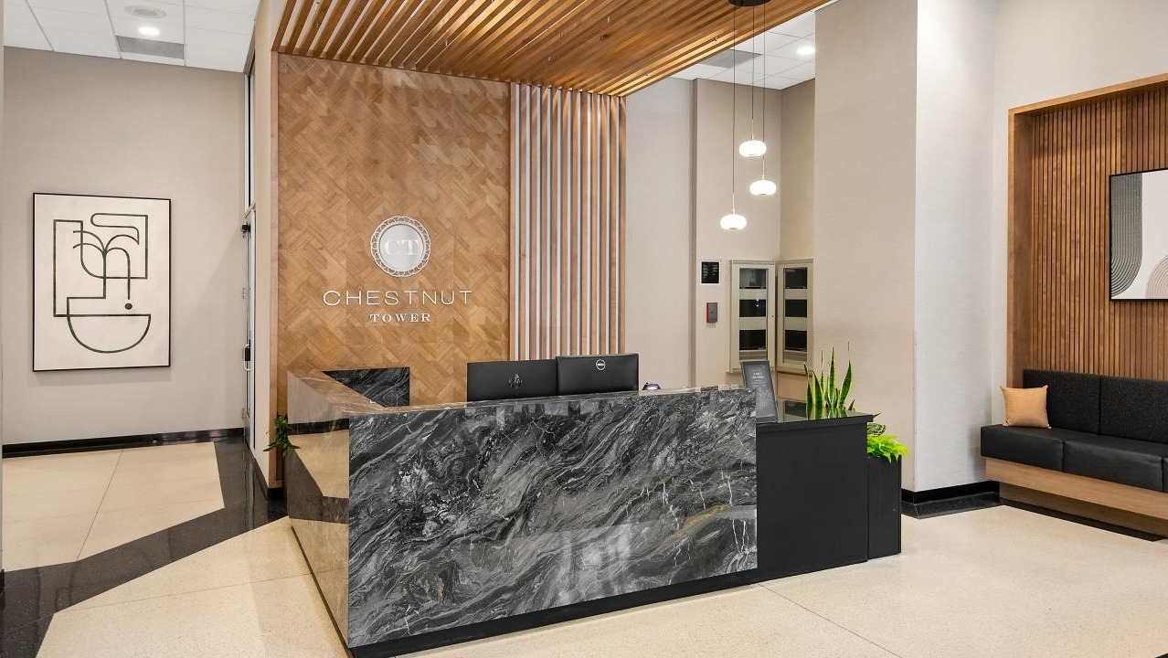 The elegant lobby at Chestnut Towers, featuring a modern front desk with a marble finish and stylish wood accents