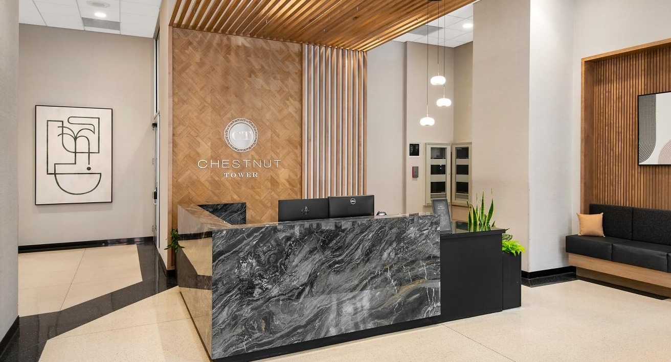 The elegant lobby at Chestnut Towers, featuring a modern front desk with a marble finish and stylish wood accents