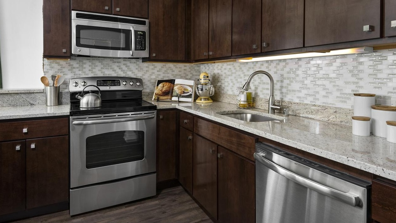 A gourmet kitchen at Chestnut Towers with dark wood cabinets, granite countertops, and stainless steel appliances
