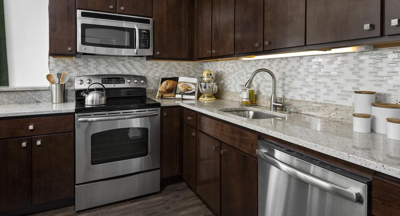 A gourmet kitchen at Chestnut Towers with dark wood cabinets, granite countertops, and stainless steel appliances