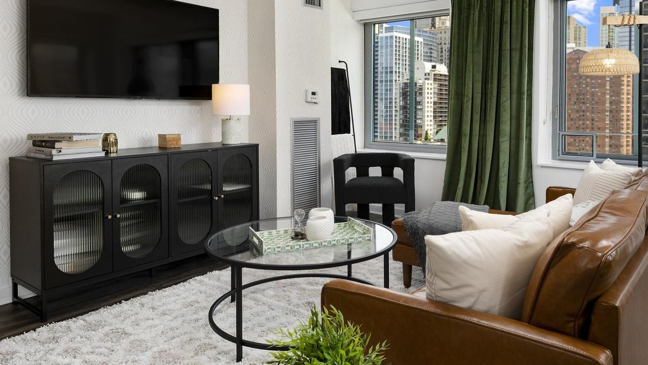 A cozy living room at Chestnut Towers with a modern media console, plush seating, and large windows with city views
